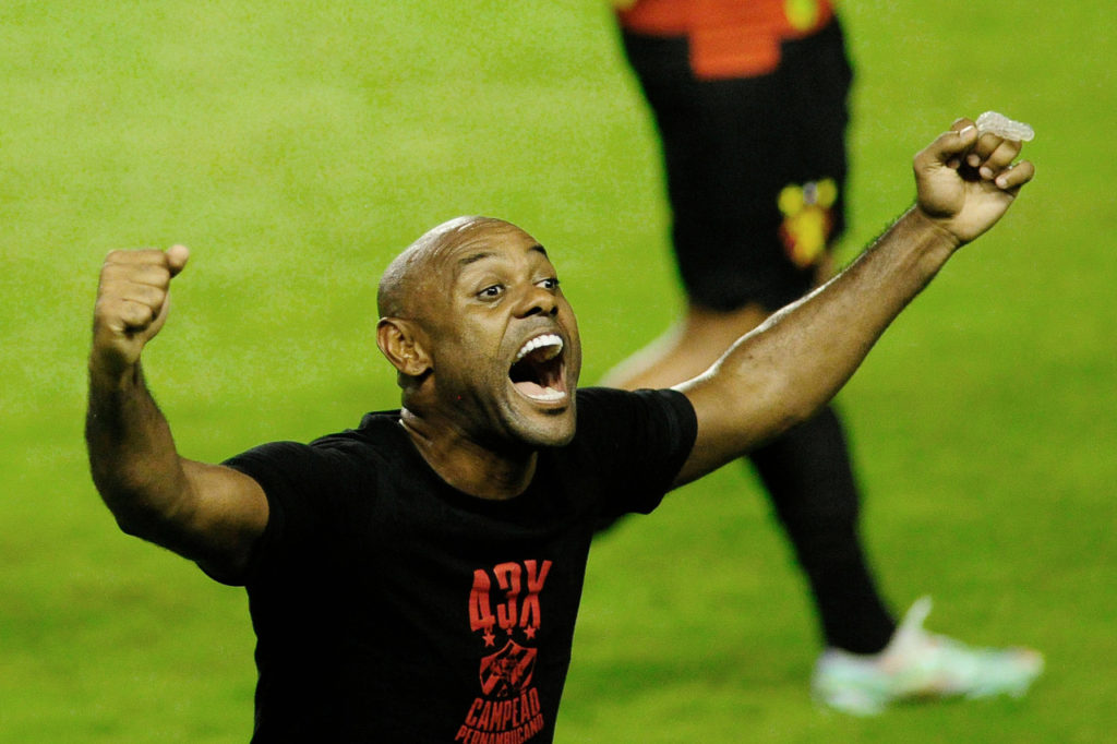 Vagner Love, atacante, levanta os braços vestindo uma camisa preta, após uma partida de futebol.
