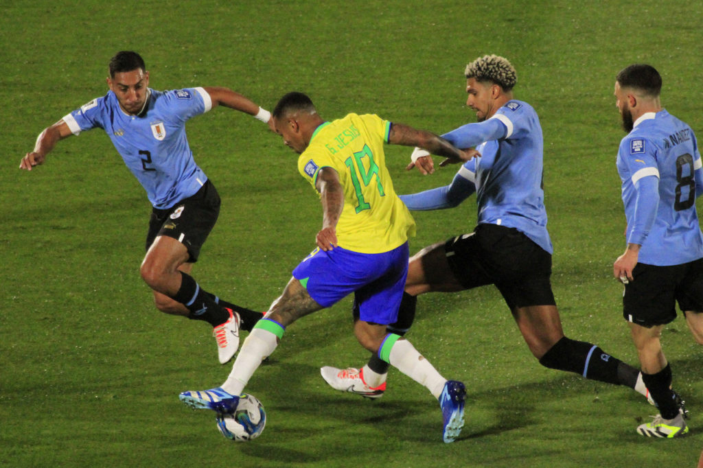 Gabriel Jesus jogando pela Seleção Brasileira e cercado por três jogadores do Uruguai.