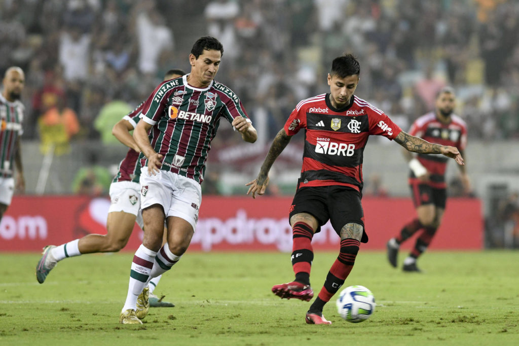 Erick Pulgar, do Flamengo, toca a bola enquanto é marcado pelo meio-campo do Fluminense Ganso.