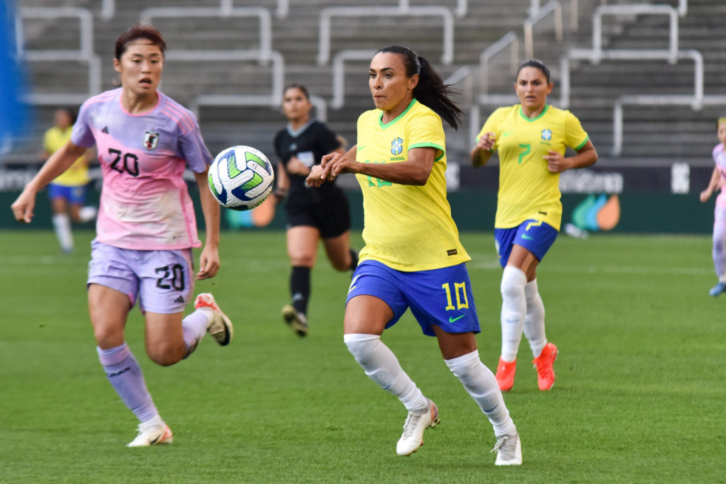 Marta, atacante da Seleção Brasileira, disputa a bola com uma adversária japonesa.