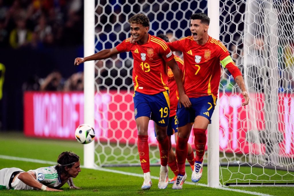 Calafiori-Yamal-Morata-gol-contra-Itália-Espanha-alamy2XD6HAR Calafiori cai no gramado após fazer gol contra na derrota da Itália para a Espanha, enquanto Lamine Yamal e Morata comemoram para a Espanha